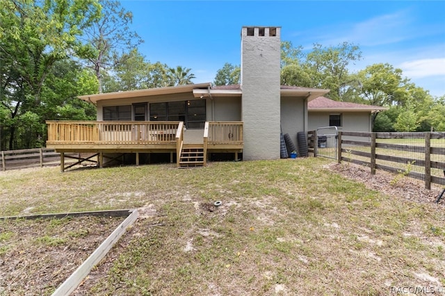 back of property with a chimney, stucco siding, a gate, fence, and a wooden deck