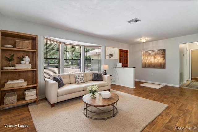 living room with wood finished floors, visible vents, and baseboards