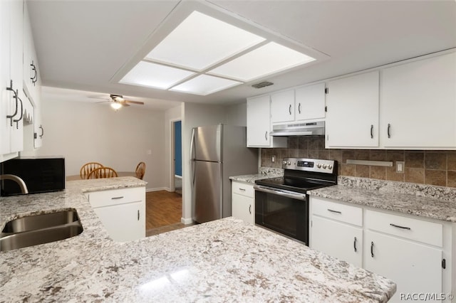 kitchen featuring appliances with stainless steel finishes, a sink, under cabinet range hood, white cabinetry, and backsplash