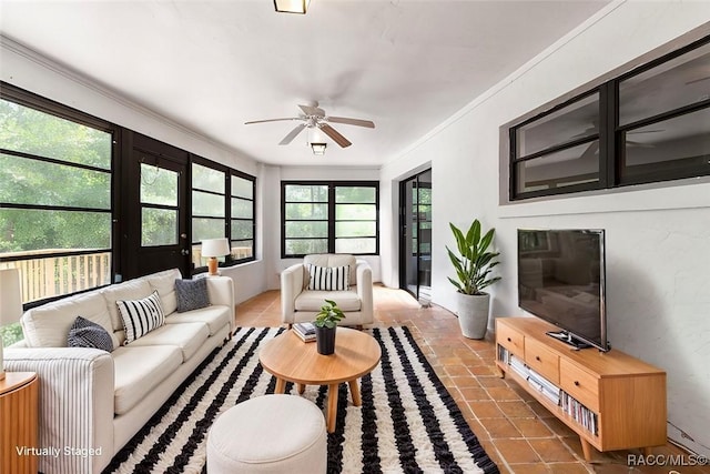 living room featuring ornamental molding, dark tile patterned flooring, and a ceiling fan