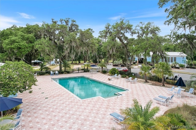 community pool with fence and a patio