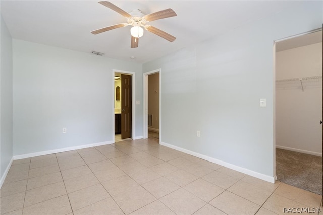 spare room featuring light tile patterned floors, a ceiling fan, visible vents, and baseboards