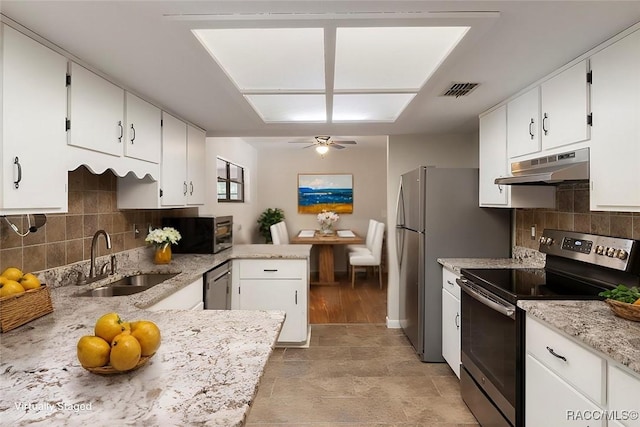 kitchen with under cabinet range hood, white cabinetry, appliances with stainless steel finishes, and a sink