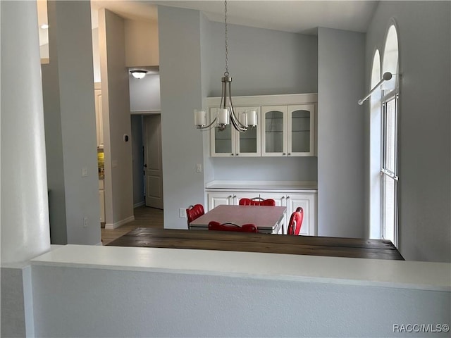 5774 N Lamp Post Dr, Beverly Hills, FL 34465 - kitchen with a chandelier, glass insert cabinets, white cabinetry, decorative light fixtures, and wood finished floors