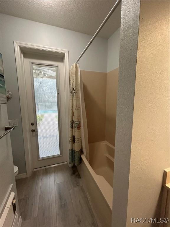 5774 N Lamp Post Dr, Beverly Hills, FL 34465 - full bath with hardwood / wood-style flooring, shower / bath combo with shower curtain, and a textured ceiling
