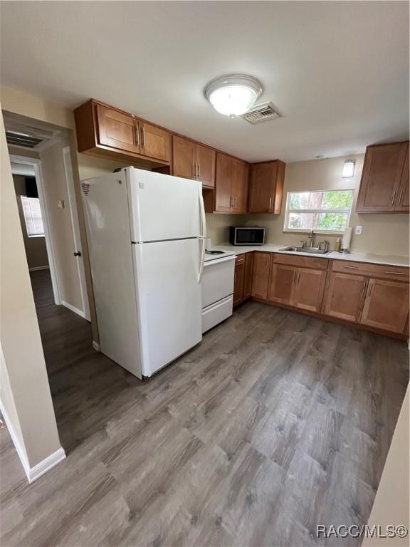 kitchen with light wood-type flooring, sink, and white appliances