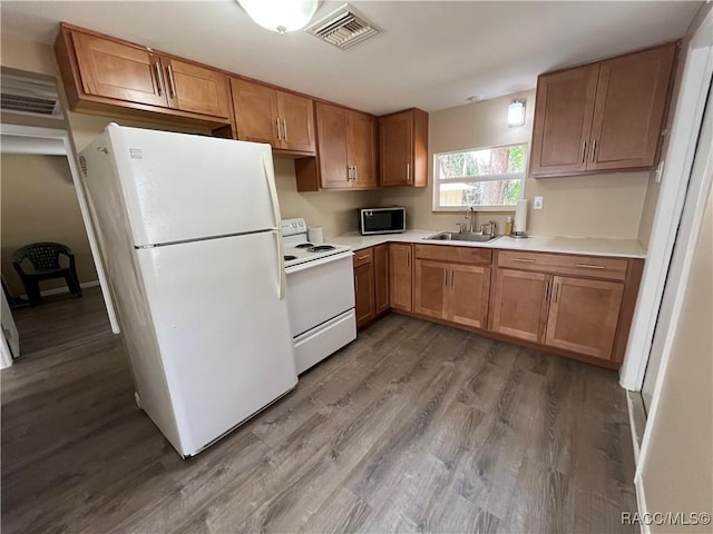 kitchen featuring wood-type flooring, sink, and white appliances