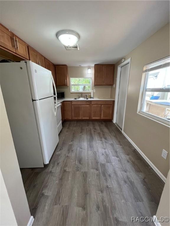 kitchen featuring dark wood-type flooring, stove, white refrigerator, and sink