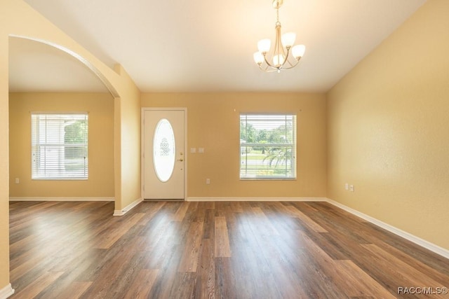 foyer entrance featuring arched walkways, a notable chandelier, wood finished floors, and a healthy amount of sunlight