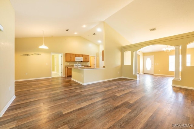 unfurnished living room with visible vents, arched walkways, dark wood-style flooring, ornate columns, and high vaulted ceiling