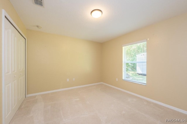 unfurnished bedroom with light carpet, a closet, baseboards, and visible vents