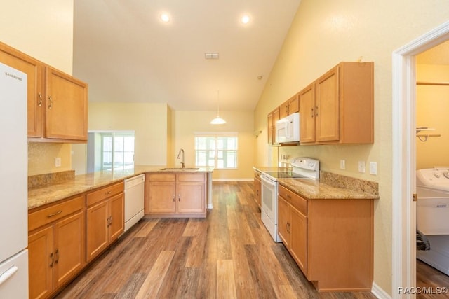 kitchen featuring a sink, white appliances, light wood-style floors, a peninsula, and light stone counters