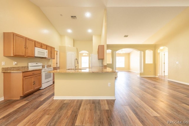 kitchen with white appliances, light wood-style flooring, arched walkways, visible vents, and a sink
