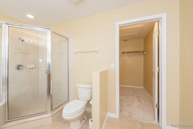 bathroom with toilet, a stall shower, a walk in closet, and tile patterned floors