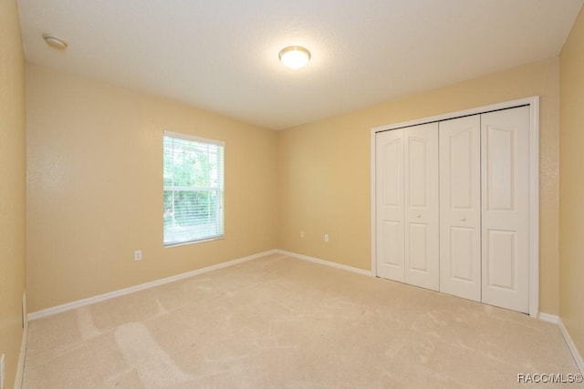 unfurnished bedroom featuring carpet floors, baseboards, and a closet