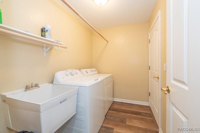 laundry area with baseboards, separate washer and dryer, a sink, laundry area, and wood finished floors