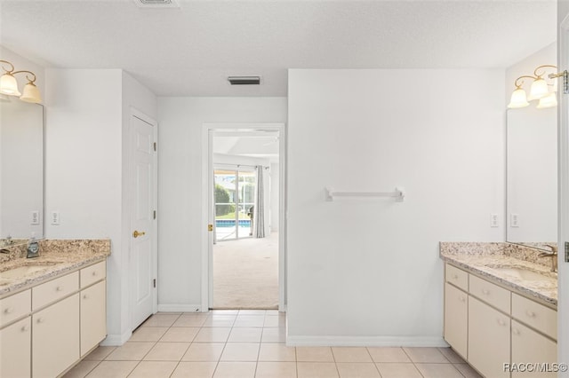 bathroom with tile patterned flooring, vanity, and a textured ceiling