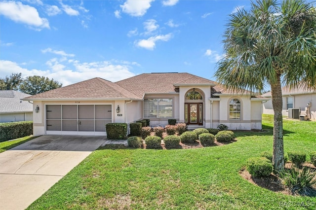 view of front of home with a front lawn, a garage, and cooling unit