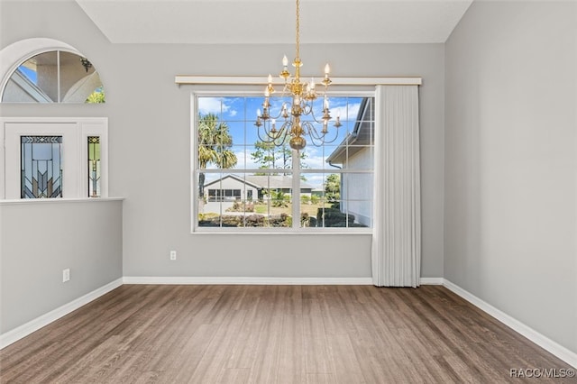 unfurnished dining area featuring a chandelier and wood-type flooring