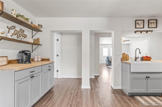 interior space with a textured ceiling, ceiling fan, sink, hardwood / wood-style flooring, and gray cabinets