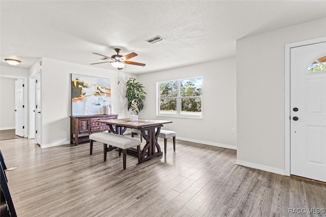 dining area with ceiling fan, light hardwood / wood-style floors, and a textured ceiling