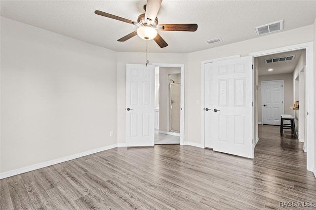 unfurnished bedroom featuring a closet, ceiling fan, dark hardwood / wood-style flooring, and a textured ceiling