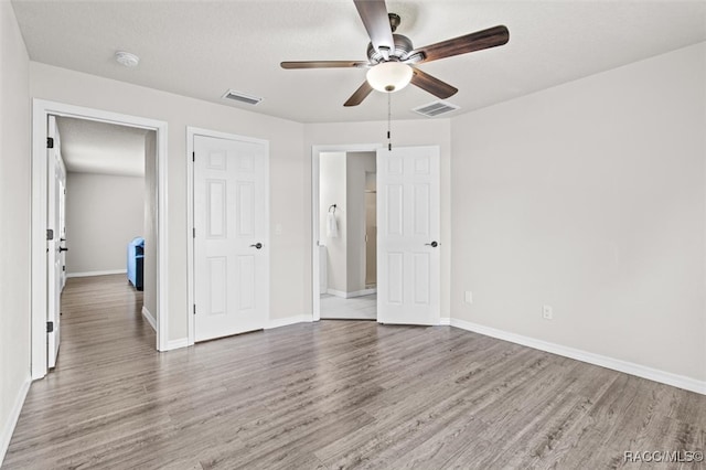 unfurnished bedroom featuring hardwood / wood-style flooring, ceiling fan, and a textured ceiling