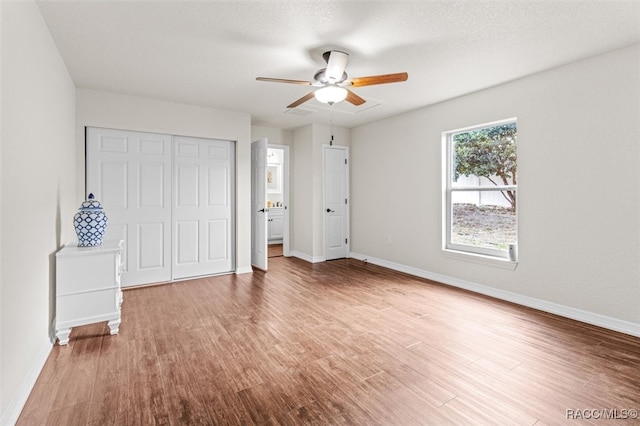 unfurnished bedroom featuring a closet, ceiling fan, hardwood / wood-style floors, and a textured ceiling