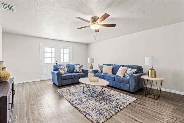 living room with french doors, wood-type flooring, a textured ceiling, and ceiling fan