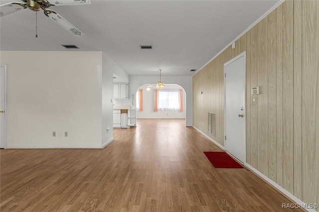732 Wharton Ter, Inverness, FL 34450 - unfurnished living room featuring ceiling fan, arched walkways, wood finished floors, and wood walls