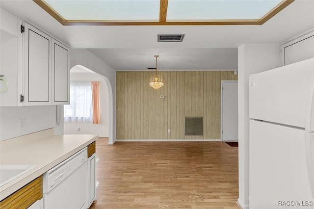 732 Wharton Ter, Inverness, FL 34450 - kitchen featuring white appliances, arched walkways, light countertops, light wood finished floors, and wood walls