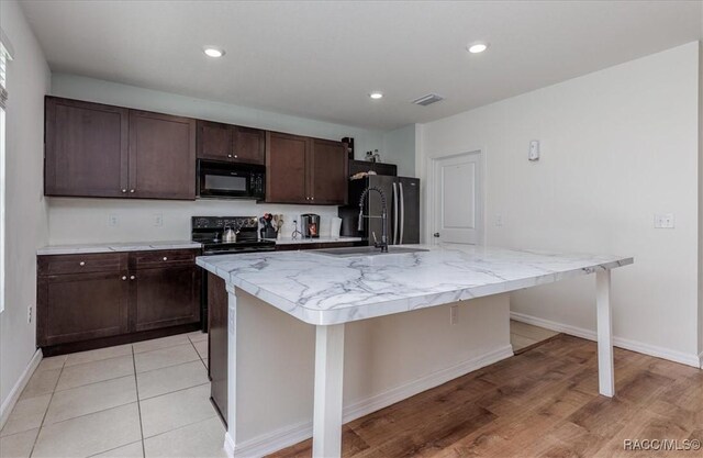 483 W Runyon Loop, Beverly Hills, FL 34465 - kitchen featuring black appliances, dark brown cabinetry, a sink, a center island with sink, and baseboards
