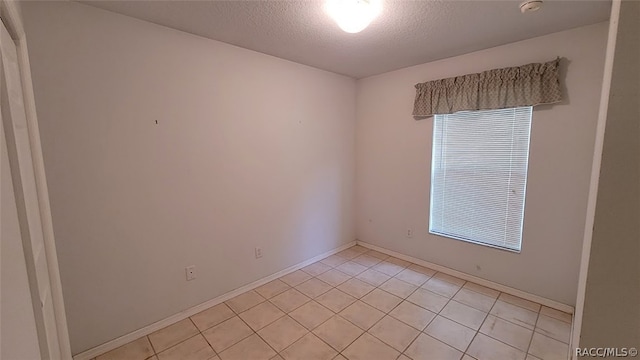 tiled spare room with plenty of natural light and a textured ceiling