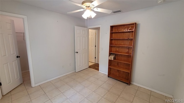 unfurnished bedroom featuring light tile patterned floors, a walk in closet, a closet, and ceiling fan