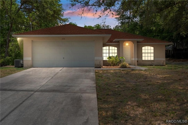 ranch-style house with central AC, driveway, an attached garage, and stucco siding