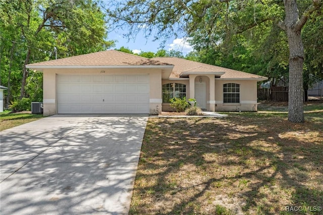 ranch-style house with fence, cooling unit, stucco siding, concrete driveway, and an attached garage