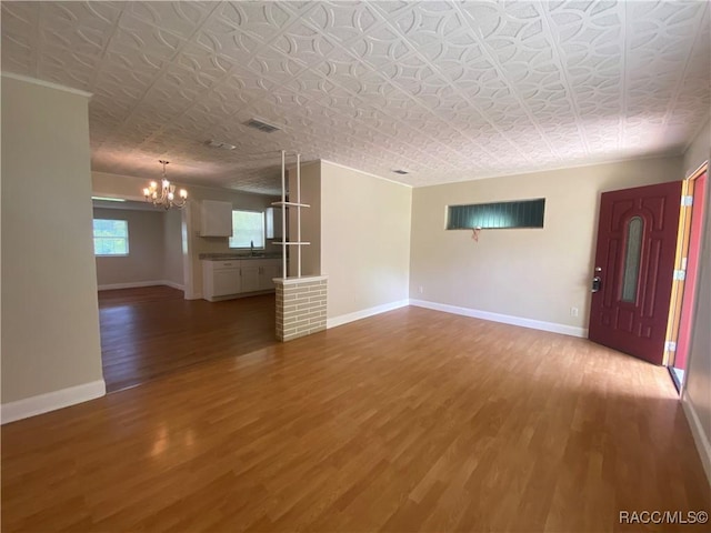 5175 E Tangelo Ln, Inverness, FL 34453 - unfurnished living room featuring a chandelier, wood finished floors, baseboards, an ornate ceiling, and a sink