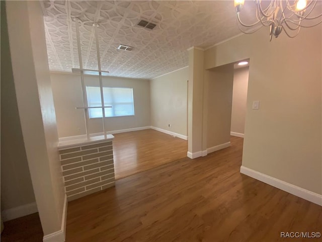 5175 E Tangelo Ln, Inverness, FL 34453 - unfurnished room featuring wood finished floors, a chandelier, an ornate ceiling, baseboards, and crown molding