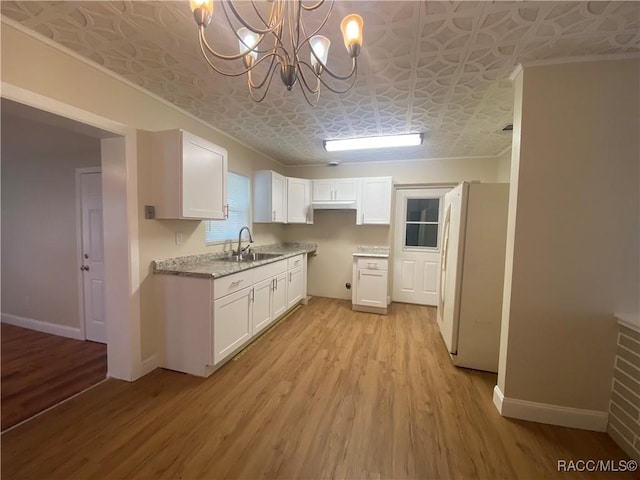 5175 E Tangelo Ln, Inverness, FL 34453 - kitchen with freestanding refrigerator, a sink, an ornate ceiling, light wood-type flooring, and white cabinetry