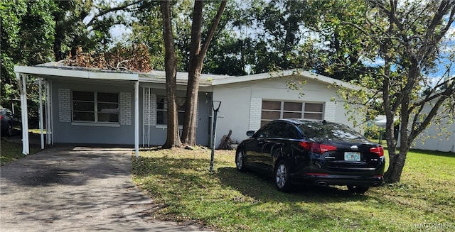 ranch-style home featuring a carport and a front lawn