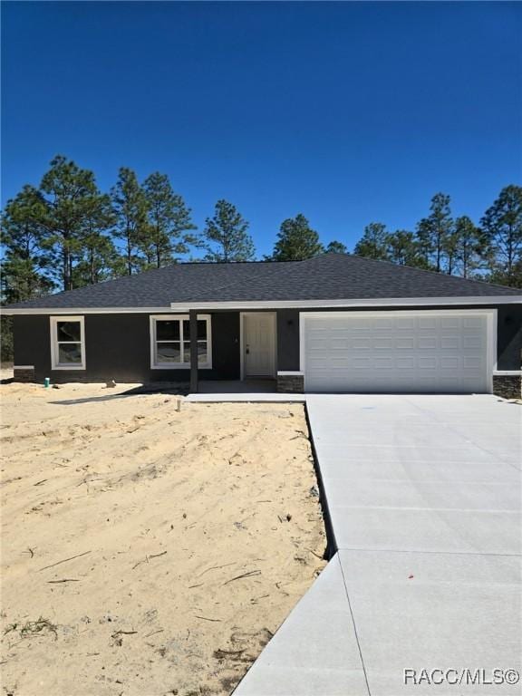 single story home with a shingled roof, concrete driveway, and an attached garage