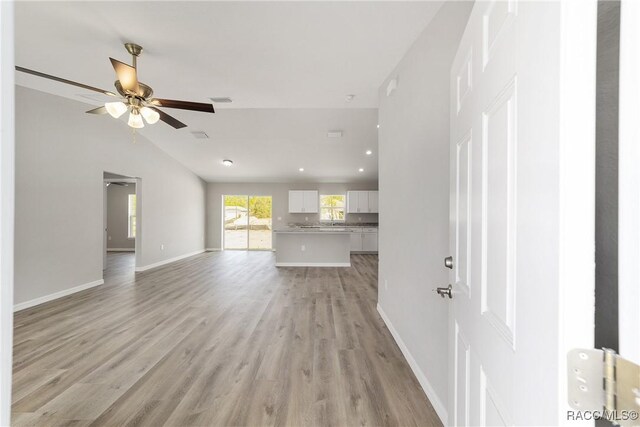 2114 W Magenta Dr, Citrus Springs, FL 34434 - unfurnished living room featuring baseboards, visible vents, ceiling fan, vaulted ceiling, and light wood-style floors