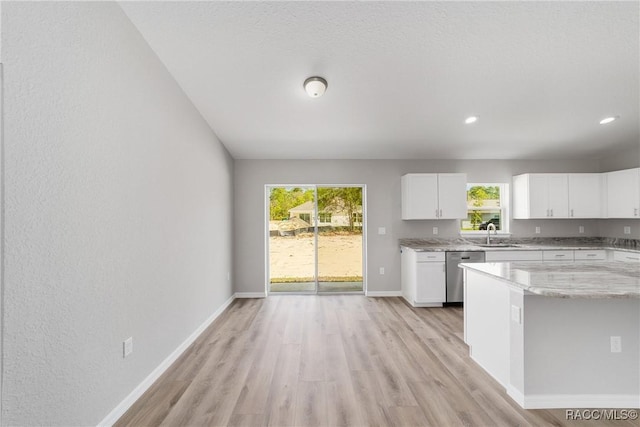 2114 W Magenta Dr, Citrus Springs, FL 34434 - kitchen featuring stainless steel dishwasher, light stone counters, light wood finished floors, a sink, and white cabinetry