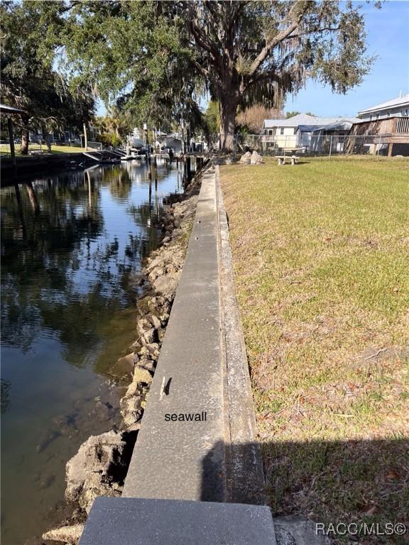 view of dock featuring a lawn and a water view