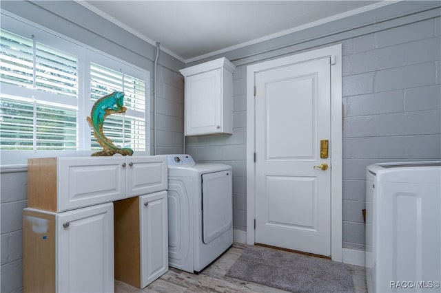 clothes washing area with independent washer and dryer, light hardwood / wood-style flooring, and cabinets