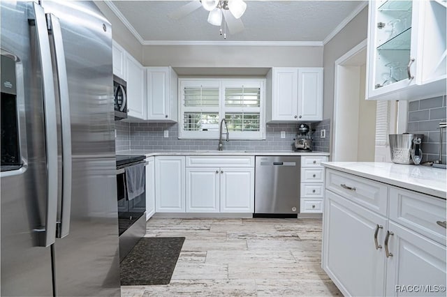 kitchen featuring sink, white cabinetry, crown molding, stainless steel appliances, and light stone countertops