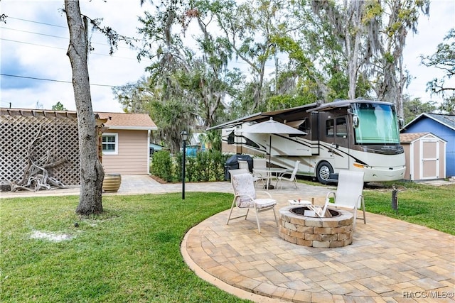 view of yard featuring a storage unit, a patio area, and a fire pit