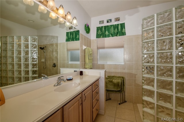 bathroom featuring a tile shower, vanity, tile patterned floors, and tile walls