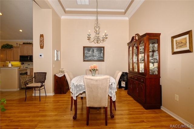 dining room with a notable chandelier, crown molding, and light hardwood / wood-style flooring