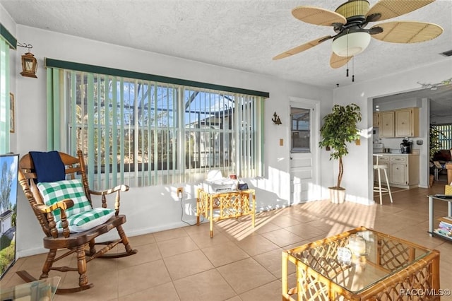 living area featuring light tile patterned floors, visible vents, a wealth of natural light, and a textured ceiling